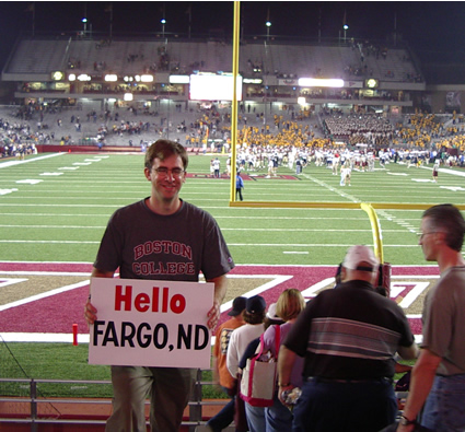 Photo at football game with sign that says "Hello Fargo"