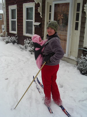 Photo of Megan on skis with infant strapped to chest
